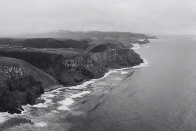 Cliffs and surf along an undeveloped stretch of coastline under low cloud